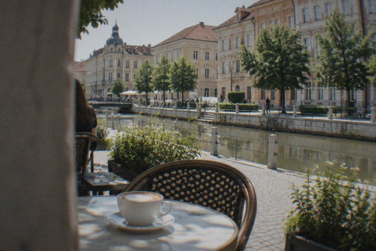 Cappuccino in a white cup on a cafe table in a sunlit square