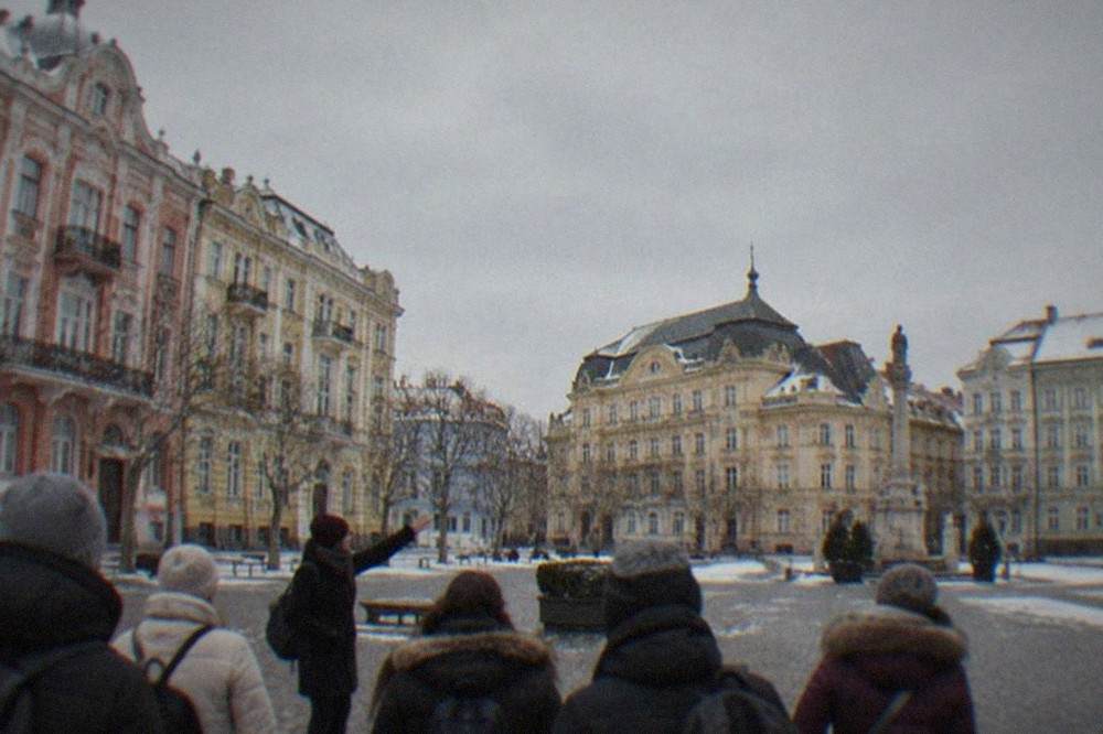 A guide leading a small group of visitors through a decorated old town square in winter