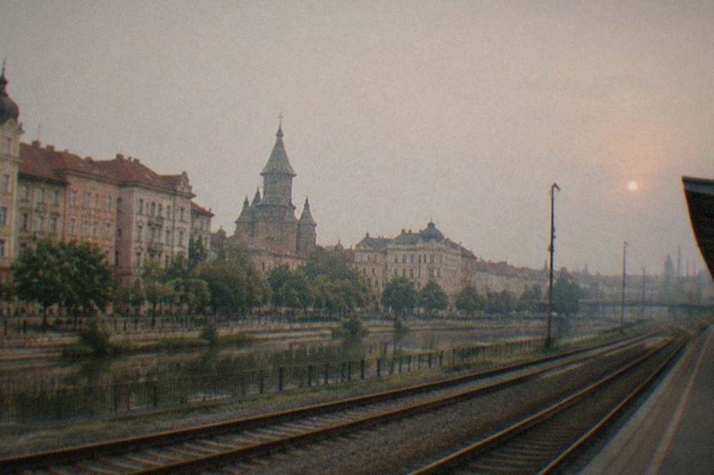 Railway tracks curving away from a city station under a dusk sky