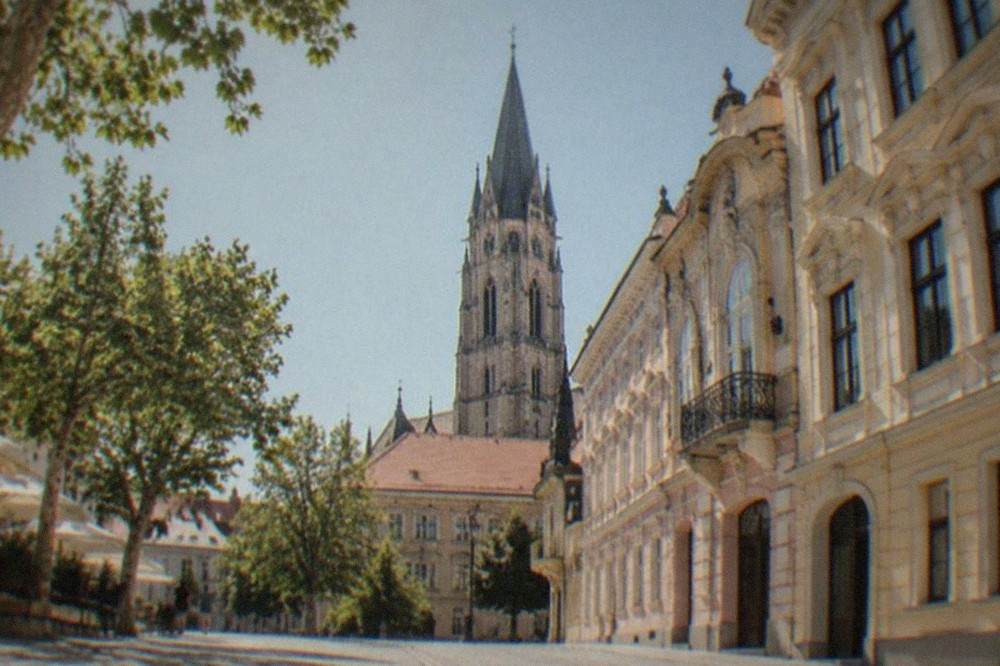 A gothic church tower rising above red-tiled rooftops in a Transylvanian old town
