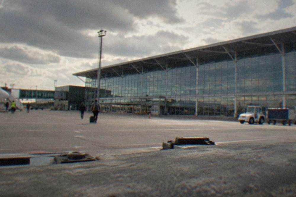 A modern airport terminal departure hall with departure boards and travelers with luggage