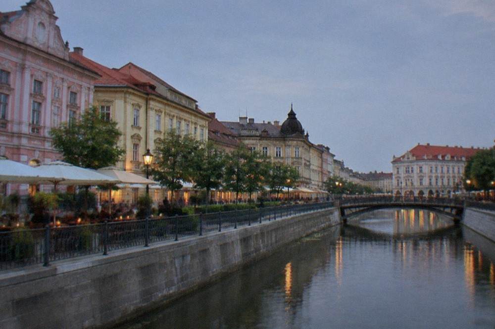 Historic baroque square with pastel buildings and outdoor cafes in Timisoara