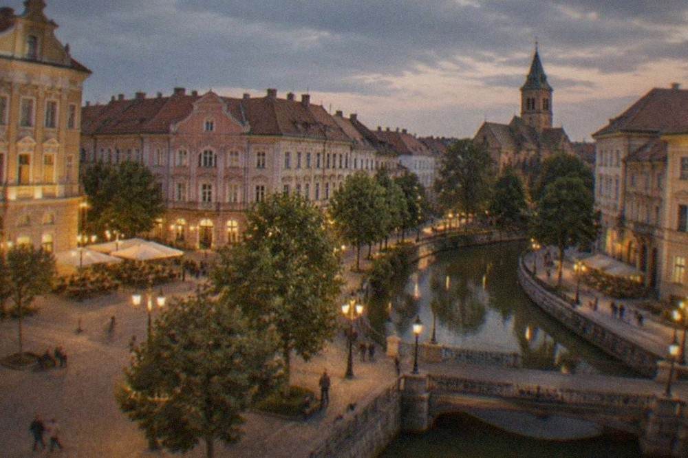 Evening view of a lit square in Timisoara with historic facades and pedestrians