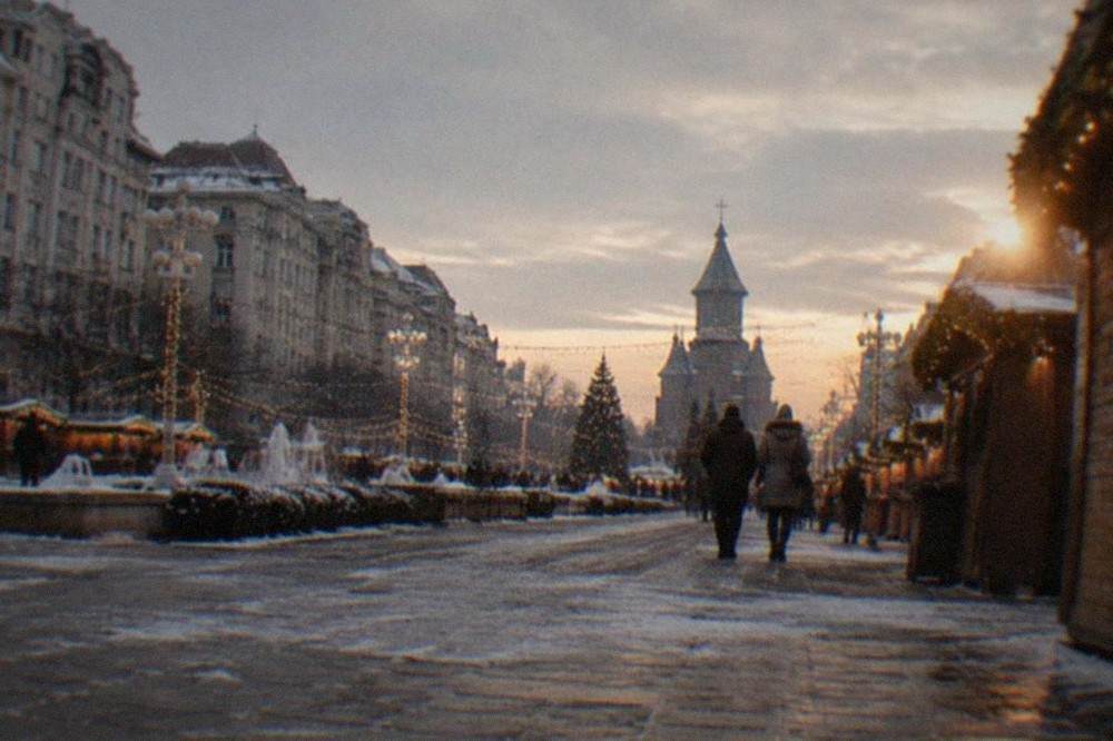 Festive lights and wooden market stalls in Victory Square in Timisoara at dusk in December