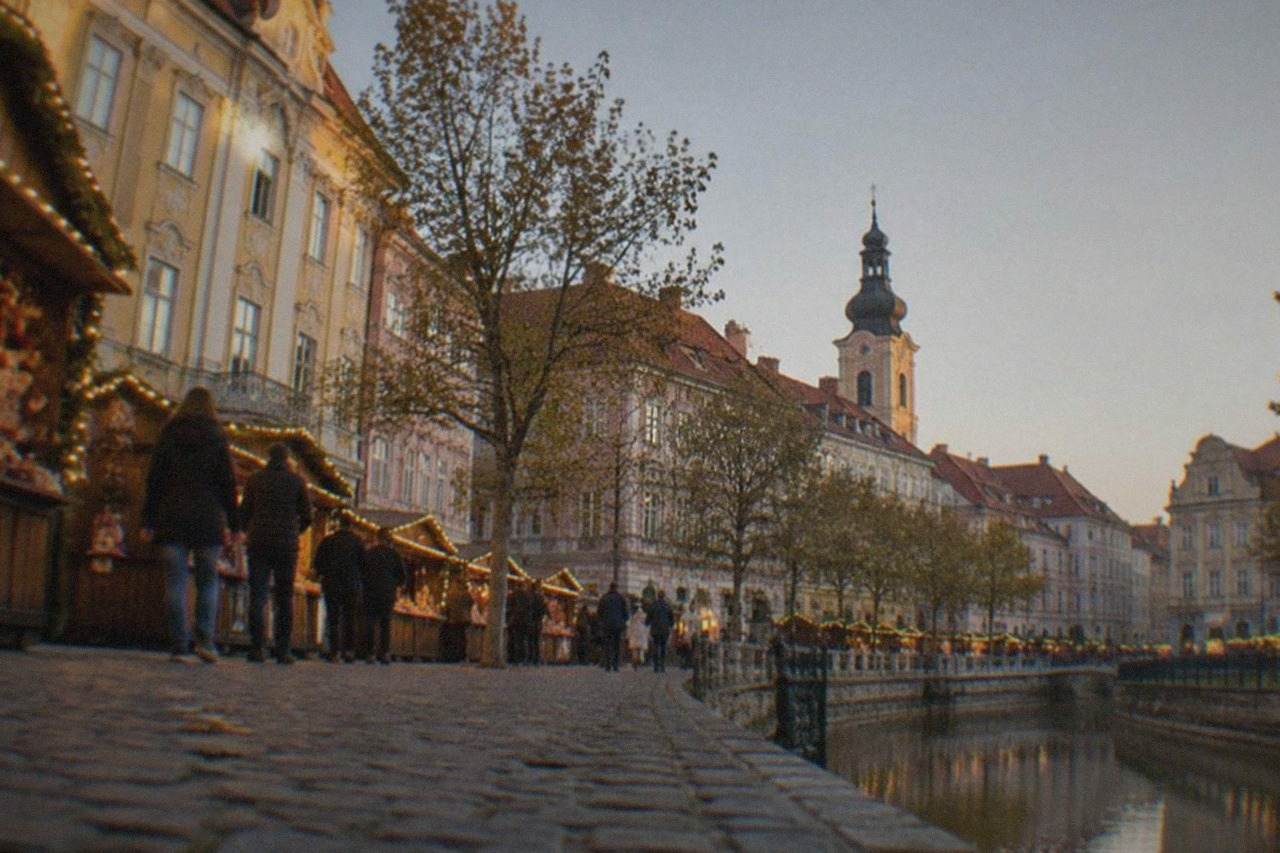 Festive wooden stalls with string lights in a European square at dusk