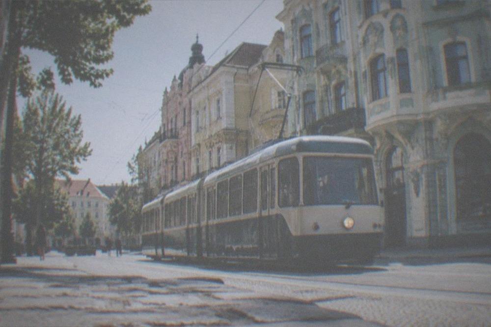 A vintage-modern tram passing colorful Secession-style buildings on a city street