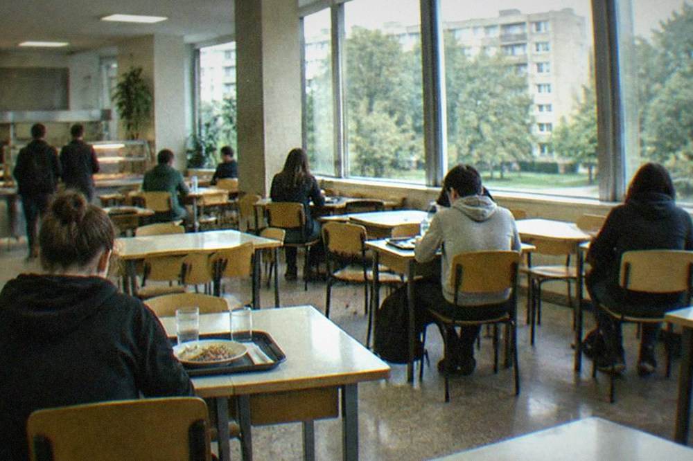 A student canteen interior with trays and simple tables at lunchtime