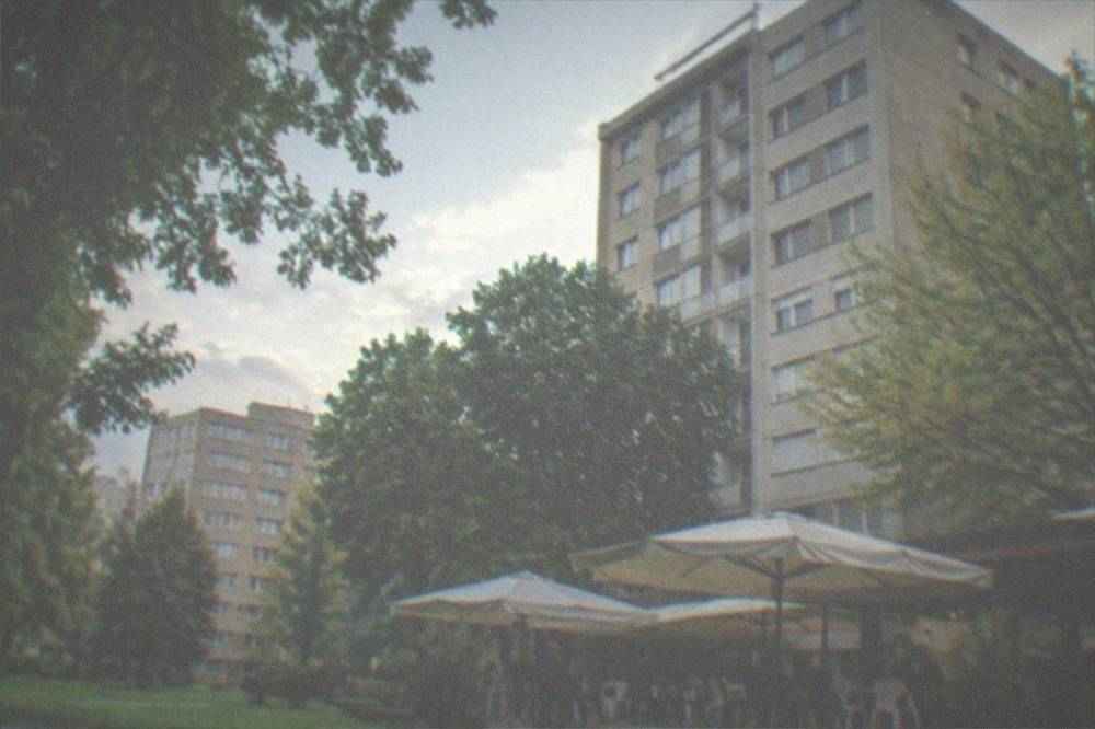 A small grill restaurant terrace with plastic chairs and umbrellas near the campus
