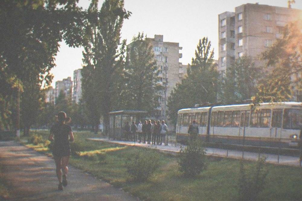 A tram passing a stop near the student campus with passengers waiting