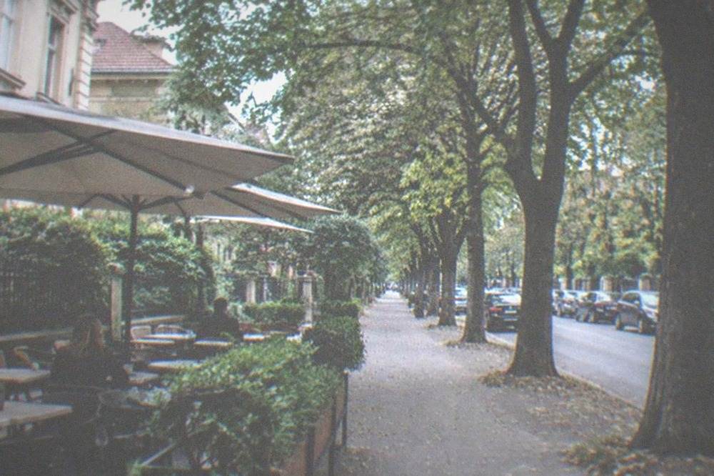 A small neighborhood cafe terrace with tables on the sidewalk under plane trees in Elisabetin