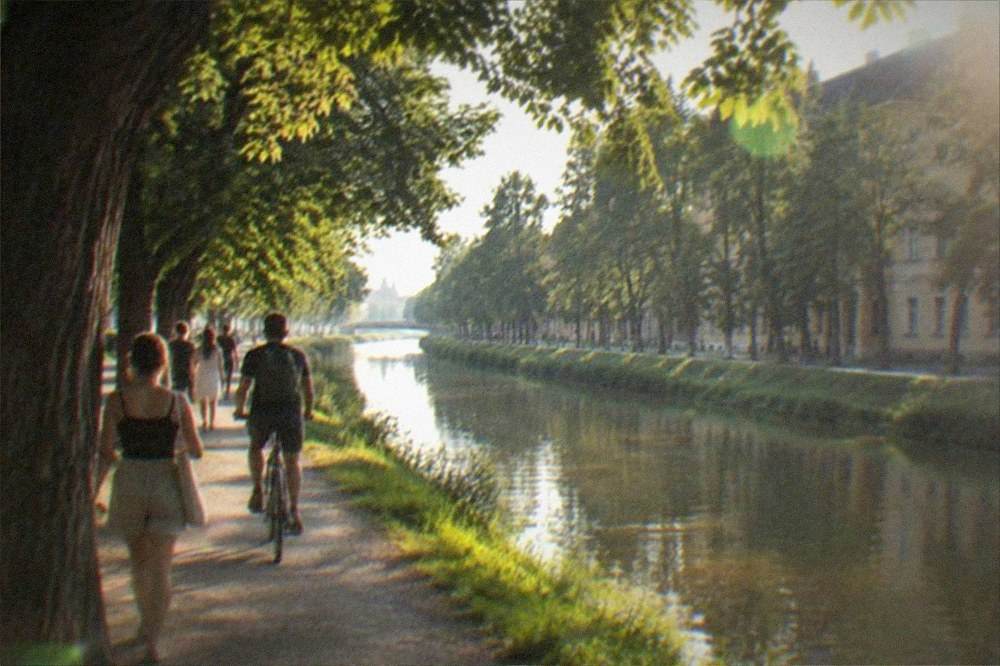 People walking and cycling along the Bega canal promenade in summer