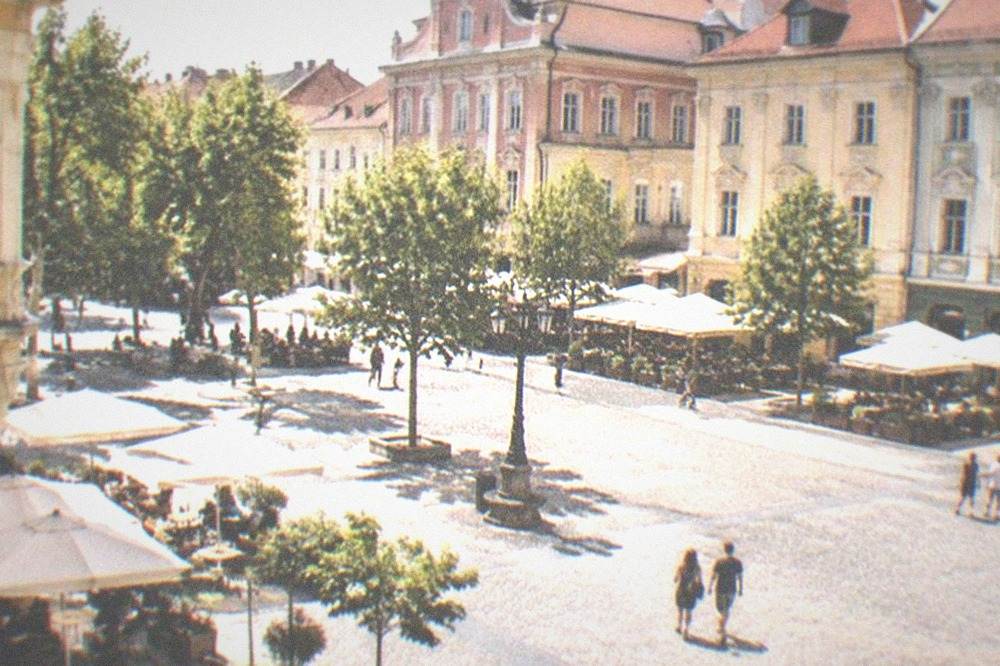 Colorful Baroque buildings and café tables around a large square in Timisoara's old town