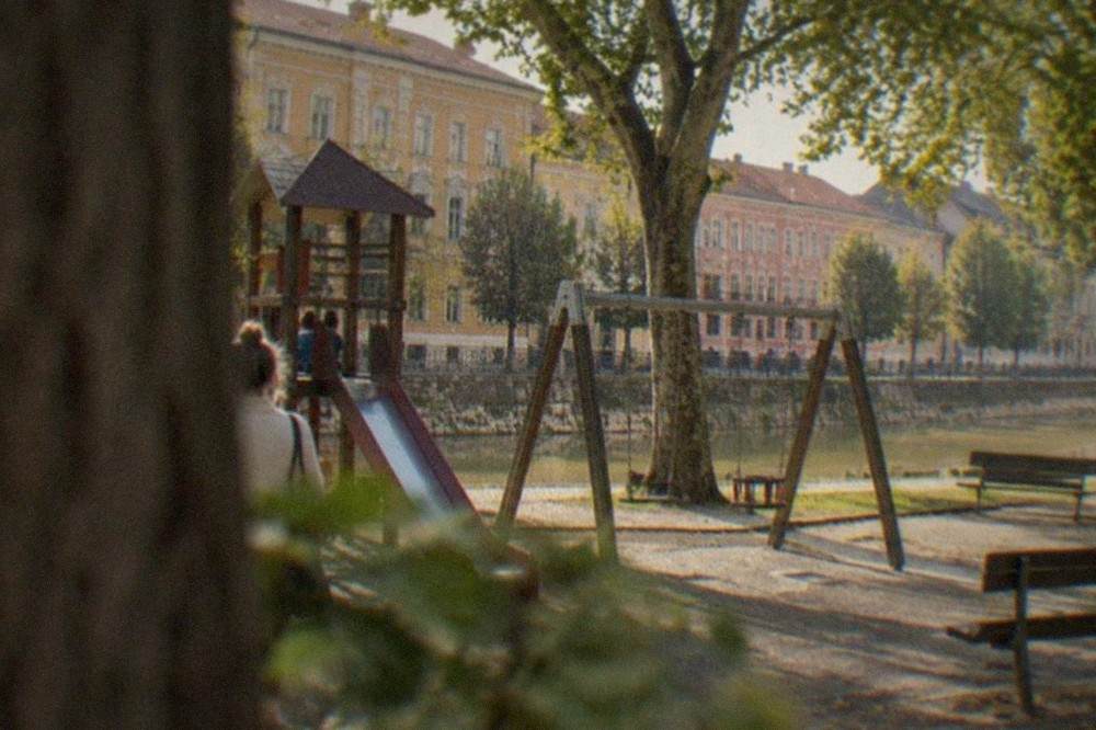 A playground with swings and slides under mature trees in a Timisoara park