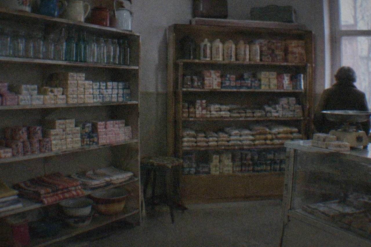 A dimly lit room with shelves of vintage household objects and packaged goods from communist-era Romania