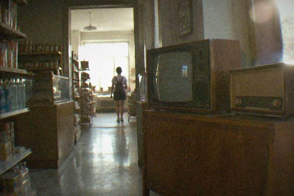 A vintage Romanian television set and radio displayed on a wooden cabinet in a museum room