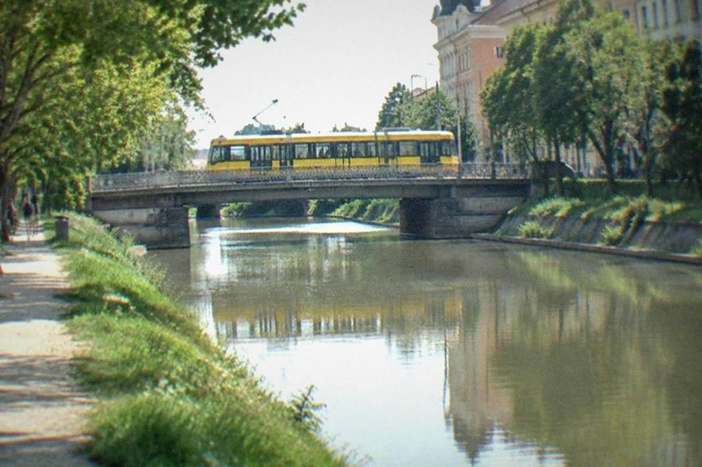 Yellow tram crossing a bridge over the Bega canal near the Fabric district