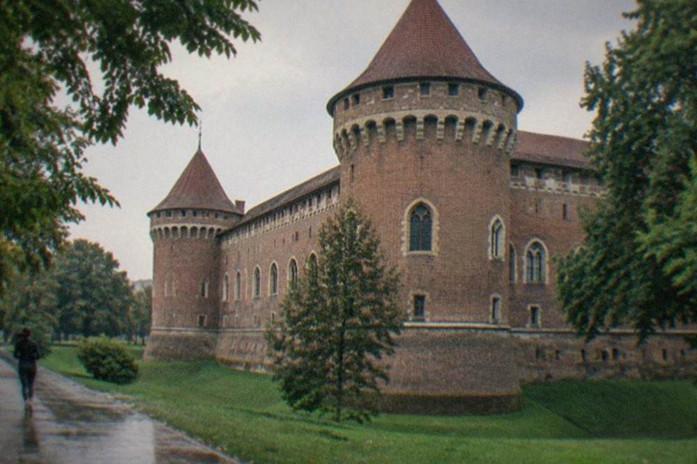 A close view of the castle's tower and arched windows from the surrounding park