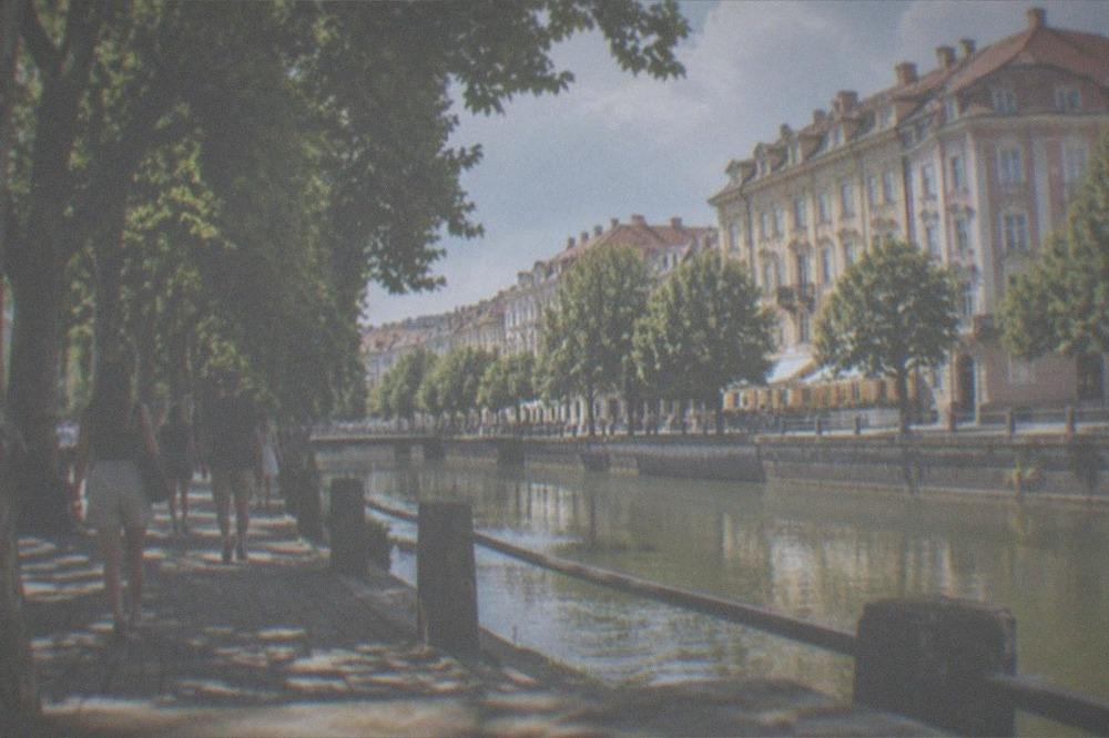 People strolling along a tree-lined canal bank in Timisoara on a summer evening