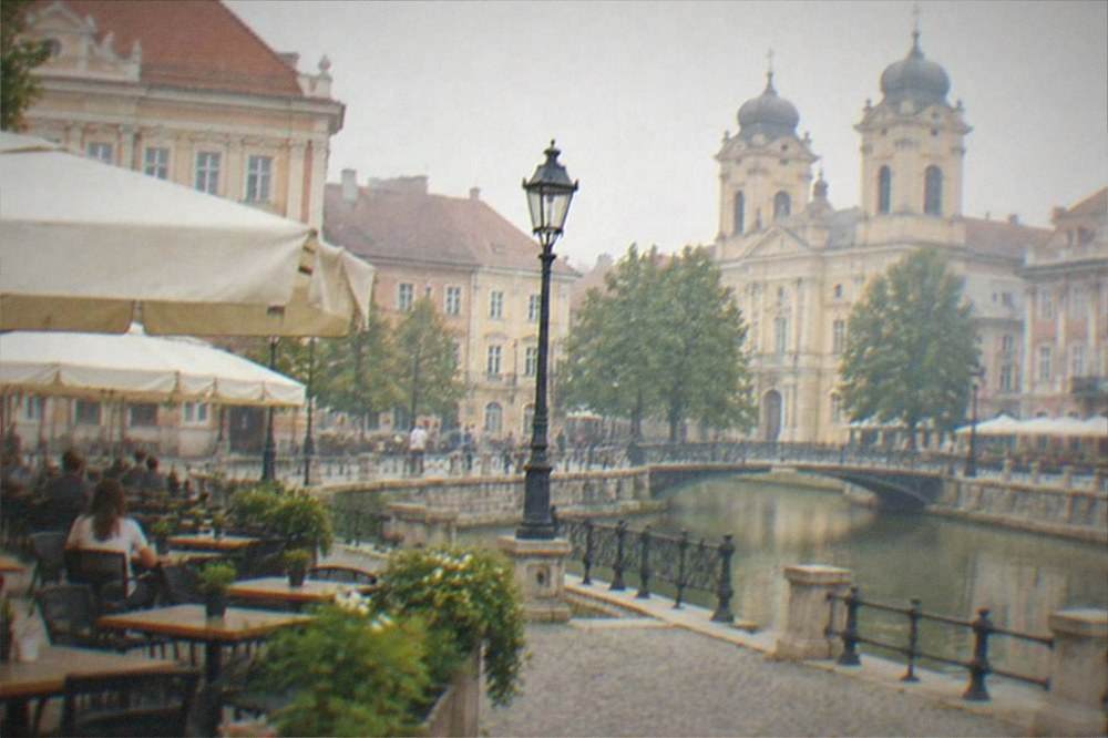 A baroque square with colorful facades and outdoor tables in central Timisoara