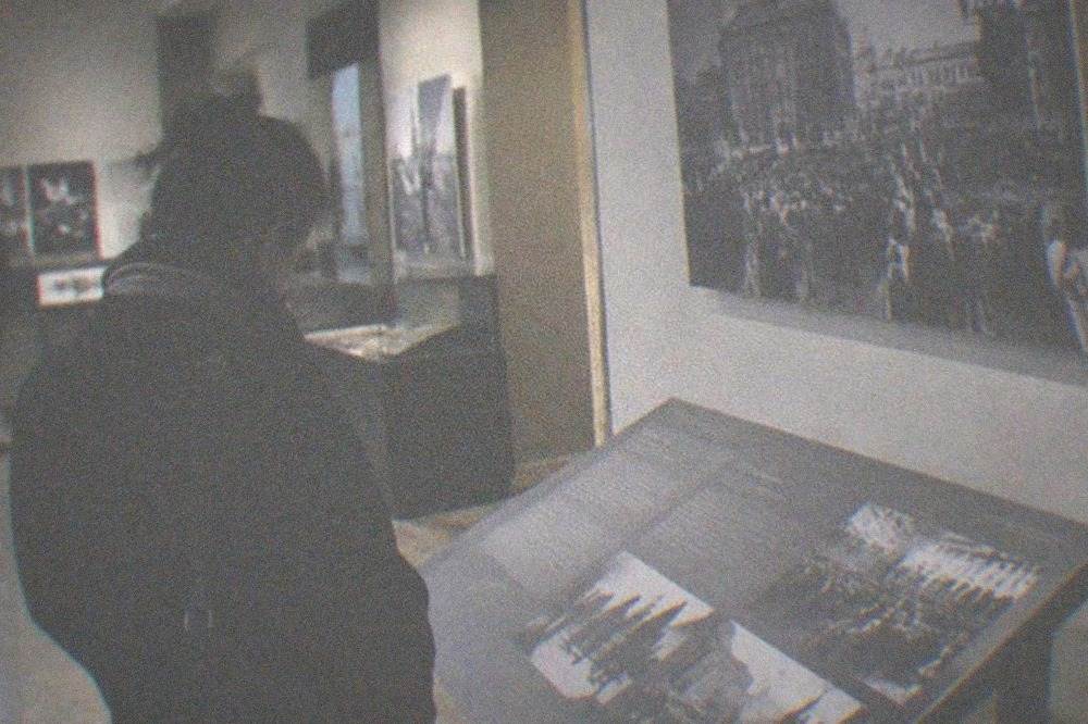 Visitor reading an information panel in a dimly lit gallery