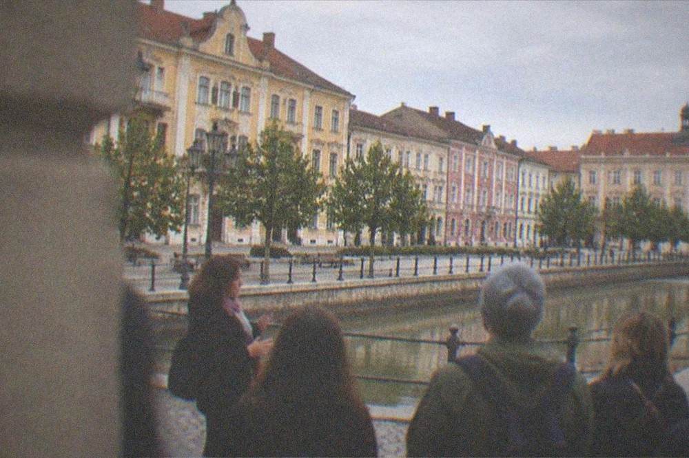 Small walking tour group listening to a guide in a Timisoara square