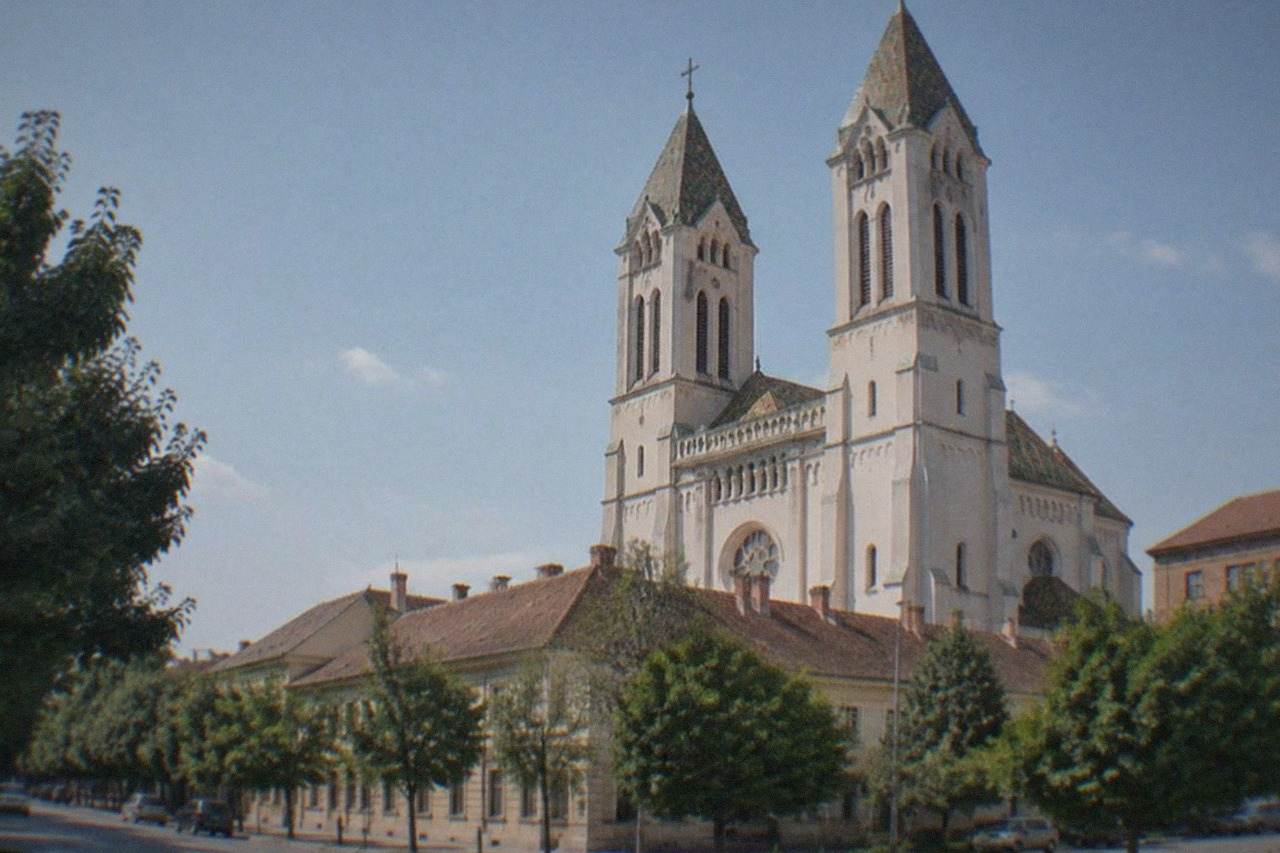 Twin towers of a large brick church rising above the rooftops of a city neighborhood