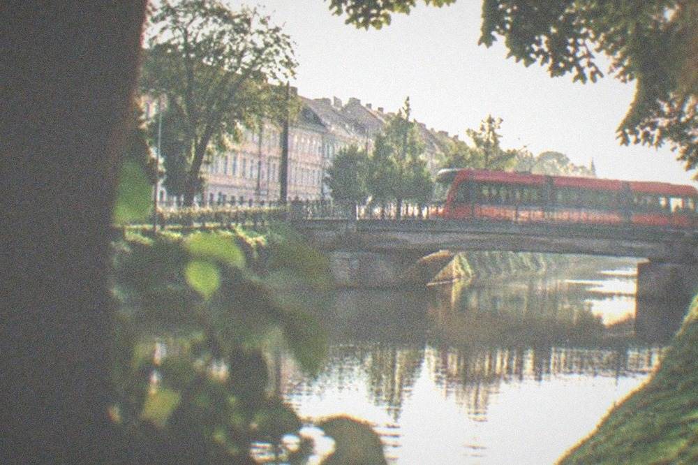 A modern red tram crossing a bridge over the Bega canal in Timisoara