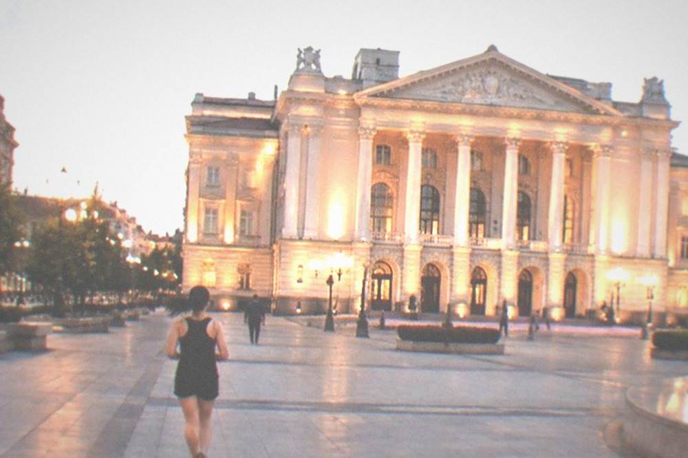 The illuminated Opera facade at dusk with the square lit in front of it