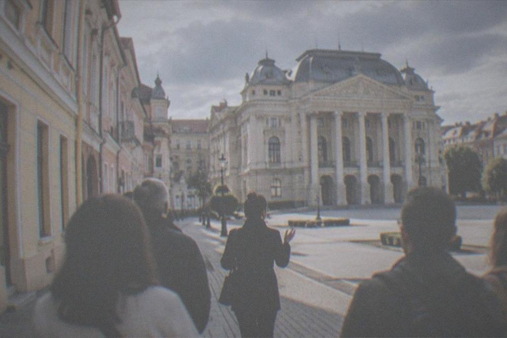 A walking guide talking to a small group on a street of colorful facades near the square