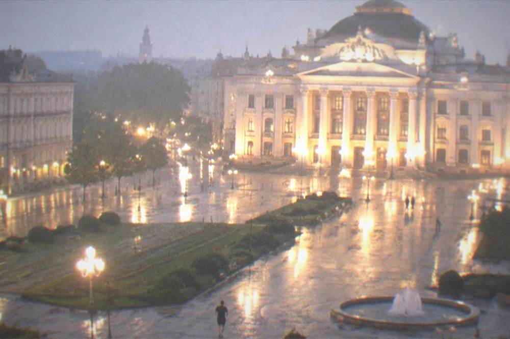 The Opera building and the square seen from above at night, lights reflecting on the pavement