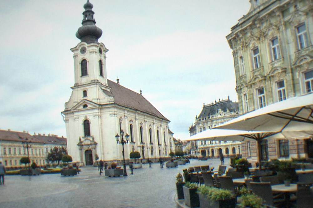 Ornate baroque square lined with pastel buildings and outdoor cafe tables