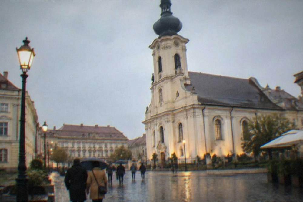 Evening light on a baroque square with people strolling between historic buildings
