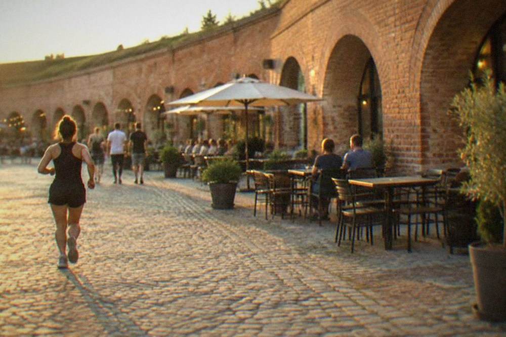 The courtyard of the Theresia Bastion with tables and people passing between the brick arches