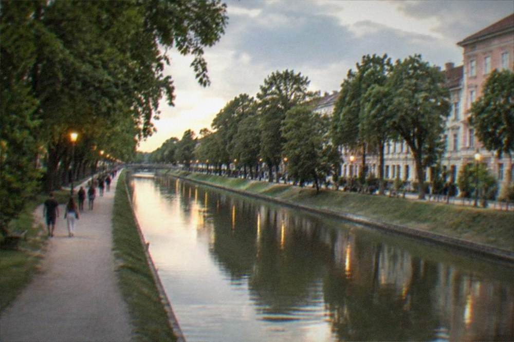 Evening lights reflecting on the Bega canal with people walking along the promenade