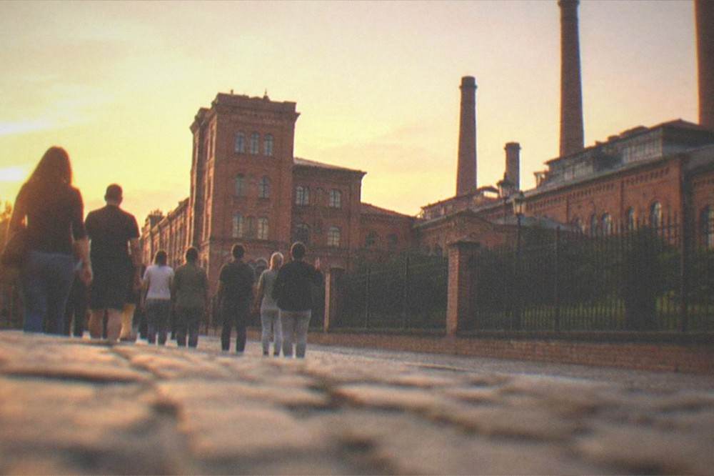 Group of visitors following a guide through an old European square at dusk