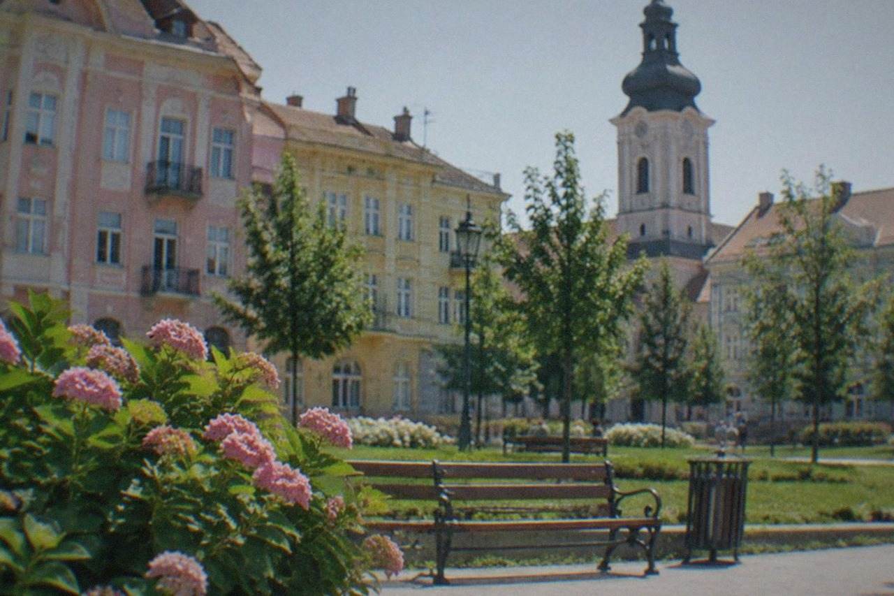 Colorful facades of historic buildings around a city square with a church tower in the background