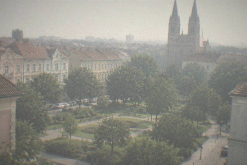 Twin towers of a large neo-gothic church rising above rooftops in an old neighborhood