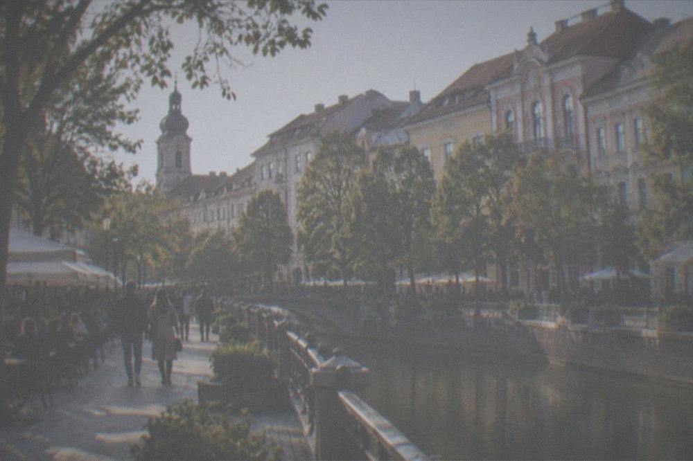Tree-lined square with outdoor seating and people strolling on a warm evening