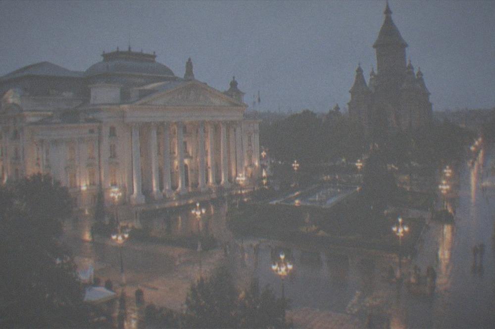 Evening view of an illuminated boulevard square with an opera house and cathedral domes