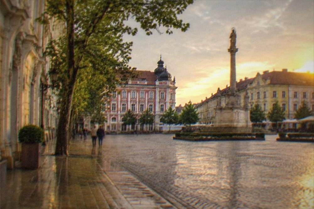 Historic monument column standing in an old town square at golden hour