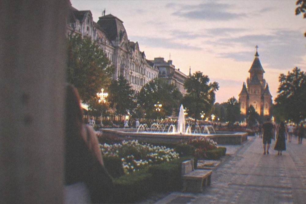 Evening view of Piata Victoriei lit up, with people walking along the promenade