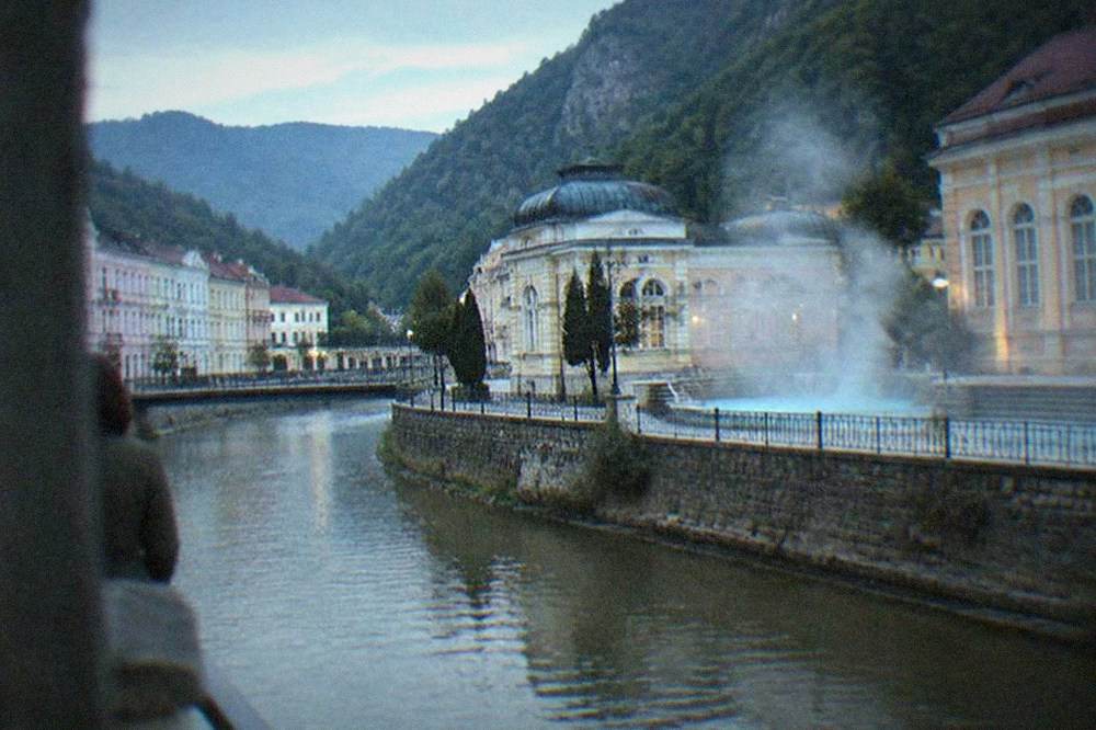 Steam rising from a thermal pool into cold morning air with mountains behind