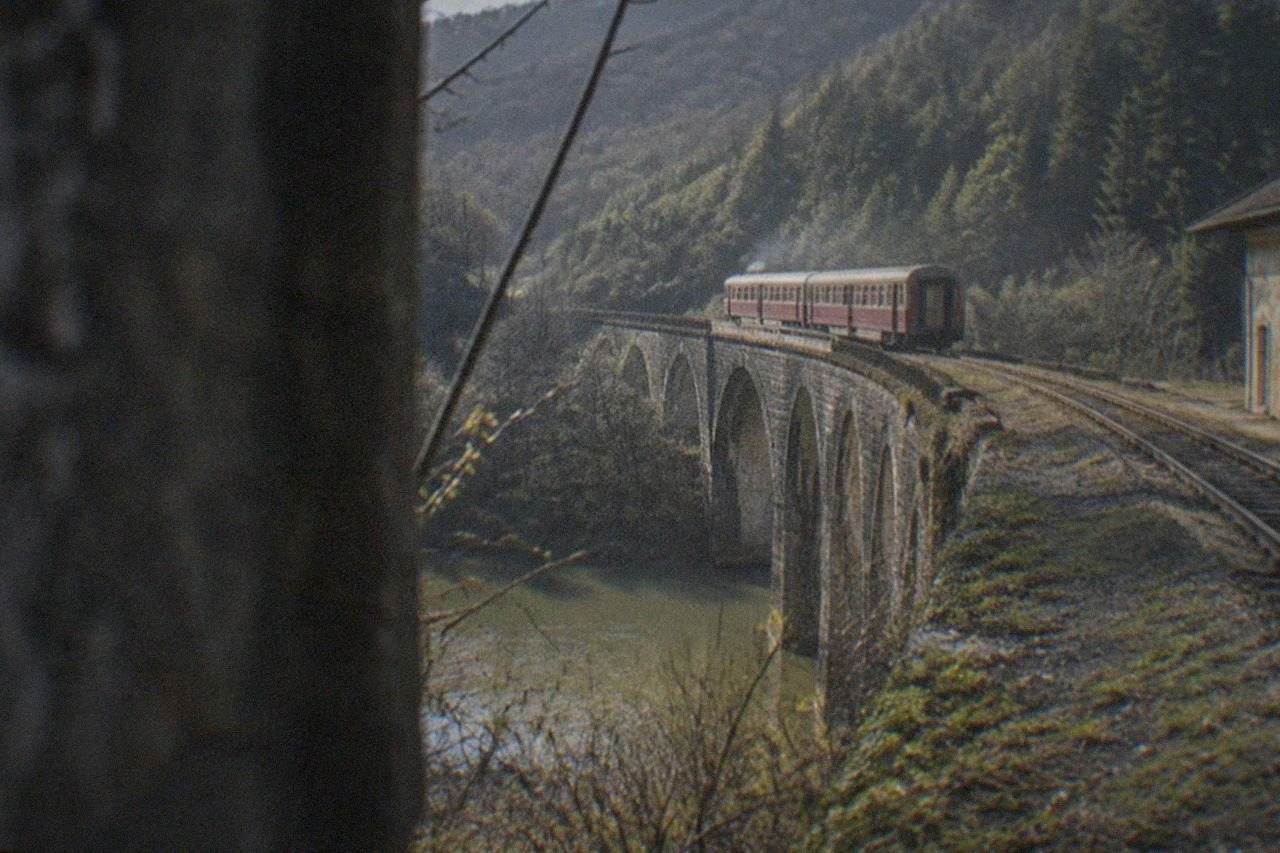 A vintage railway viaduct curving through green forested hills in the Banat mountains of Romania