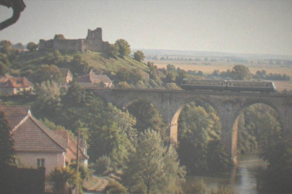 A regional train crossing a stone viaduct above a forested Banat valley