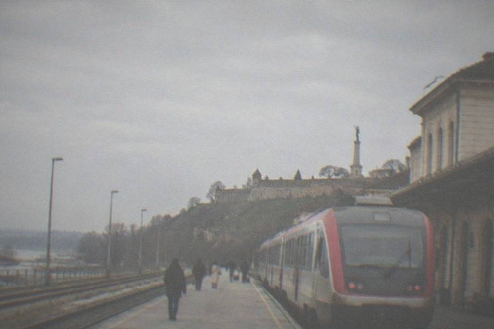 Railway platform with a regional train waiting beside a station building
