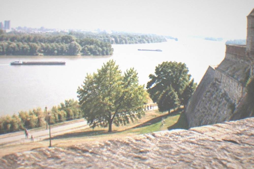 Fortress walls above a riverside park with two wide rivers meeting in the distance