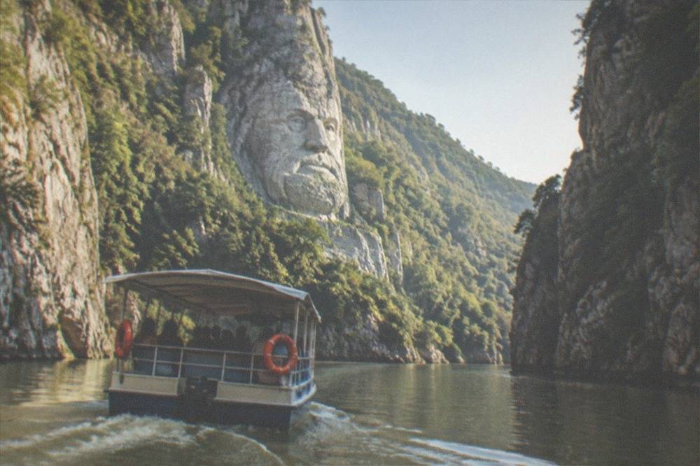 A small boat carrying sightseers along a narrow river passage between steep rocky cliffs