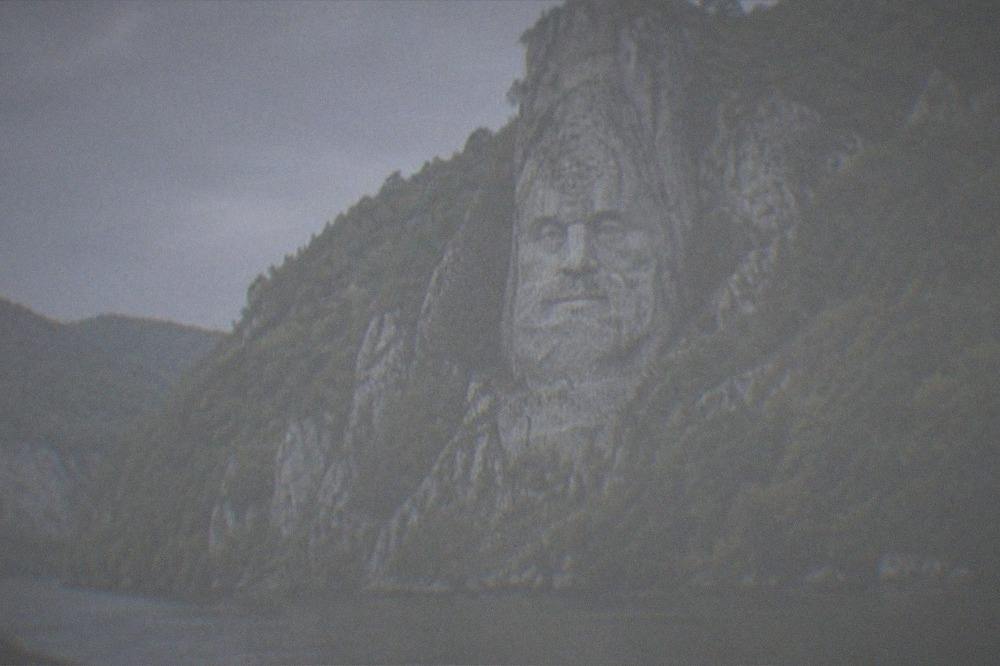The carved cliff face seen from a boat on the Danube in warm afternoon light