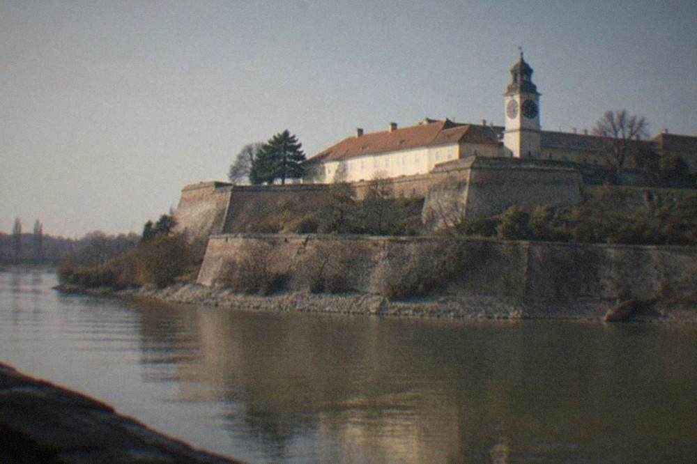 The lower walls and clock tower of Petrovaradin Fortress seen from the Danube