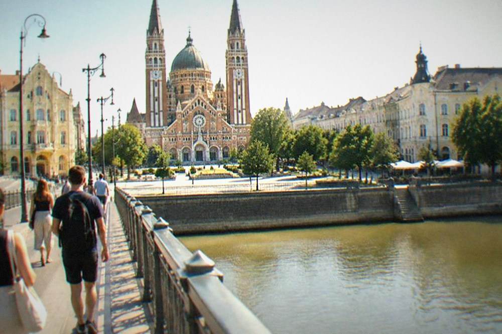 Travelers walking across a bridge over the Tisza river toward central Szeged